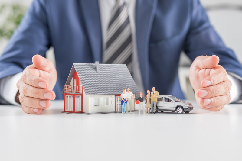 Insurance agent with miniature model of home, family, and car